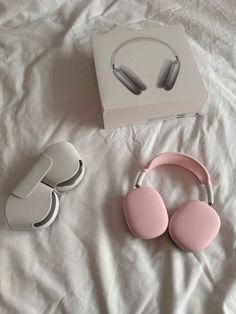 a pair of pink headphones sitting on top of a bed next to a box