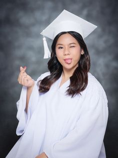 a woman in a graduation cap and gown poses for a photo with her finger up