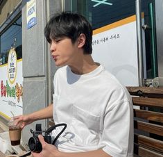 a man sitting on a bench with a camera in his hand and looking at something