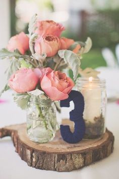 a vase filled with pink roses sitting on top of a wooden table next to a candle