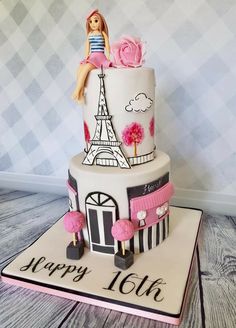 a birthday cake with the eiffel tower on top and pink flowers in front