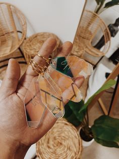 a person holding up some small pieces of glass in their hand with other items around them