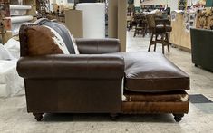 a brown leather couch sitting on top of a hard wood floor in a room filled with furniture