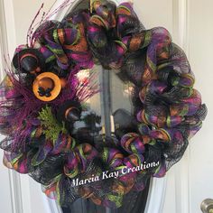 a purple and black mesh wreath with an orange bear on it's front door