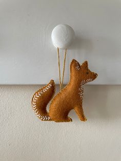 a stuffed animal hanging on the wall next to a white ball and two strings attached to it