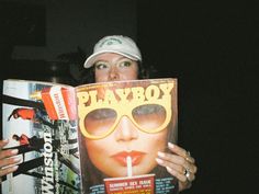 a woman is reading a magazine with sunglasses on her face and holding up the cover