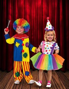 two children dressed in clown costumes holding hands and standing next to each other on a wooden floor