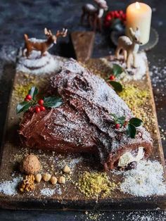 a large piece of chocolate cake on a wooden cutting board covered in powdered sugar and sprinkles