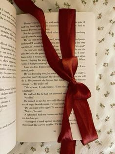 an open book with a red ribbon tied to it