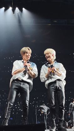 two men standing on stage with microphones in their hands