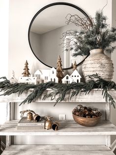 a christmas mantle with pine cones and evergreen branches on it, surrounded by other holiday decorations