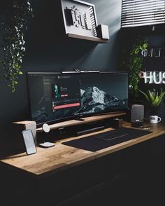 a desktop computer sitting on top of a wooden desk next to a phone and plant