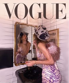 a woman in a zebra print dress is looking at her reflection in the bathroom mirror