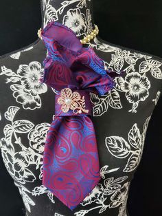 This  Blue and Red Paisley Necktie Necklace is made with a (Barry Wang) woven silk tie, and features a Rose Gold Pearl Flower Brooch strung on your choice of an adjustable Rosary Chain Ribbon Tie Pearl Necklace or an adjustable Elastic Band. The soft, comfortable fabric sits perfectly on any size chest, while the adjustable necklace feature allows you to customize the fit to your liking. Measuring at a versatile length, this necktie necklace is designed to be a one-size-fits-all. View all Women Neck Tie Necklace Diy, Elegant Multicolor Ties For Wedding, Elegant Multicolor Wedding Ties, Elegant Multicolor Brooches For Formal Occasions, Elegant Purple Flower Brooch, Purple Flower Brooch For Formal Occasions, Necktie Necklace, Queen Style, Tie Fashion