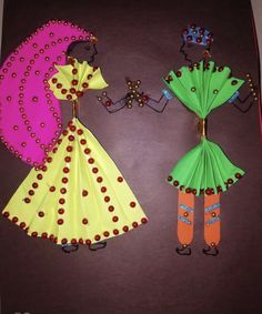 two paper dolls made to look like they are wearing dresses and holding hands with each other