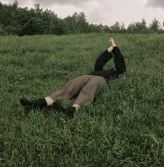 a man laying in the grass with his arms up and head above his chest, looking into the distance