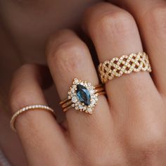 a woman's hand with three different rings on it and one has a blue stone in the middle