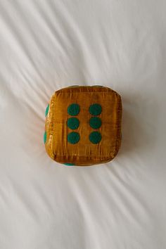 a brown and green pillow sitting on top of a white bed