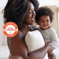 a woman holding a baby wrapped in a towel and smiling at the camera with an award badge over her left shoulder