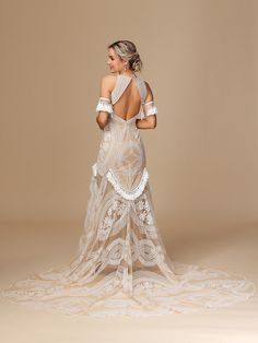 the back of a woman in a white dress with an intricate lace design on it