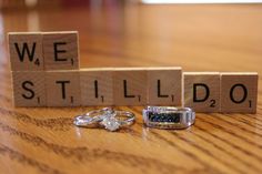 two wedding rings sitting next to scrabble blocks that spell out we still do