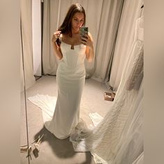 a woman taking a selfie in front of a wedding dress