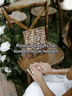 a woman sitting on top of a wooden chair next to a white rose covered table