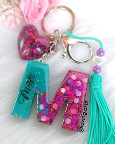 the letter m is made out of glitter and has a tassell keychain