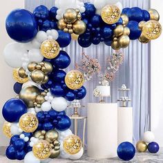 blue and white balloons are hanging from the ceiling in front of a table with vases