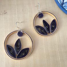 a pair of earrings sitting on top of a wooden table next to a blue plate