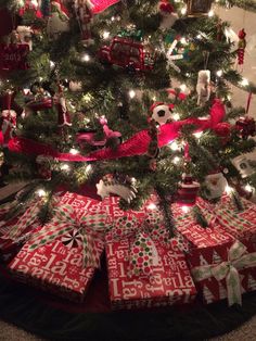 a christmas tree with presents under it and lights on the trees branches, all wrapped in red and white paper