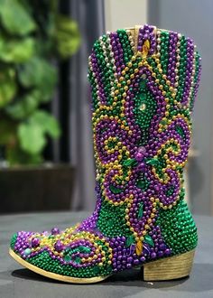 a pair of purple and green beaded boots sitting on top of a black table