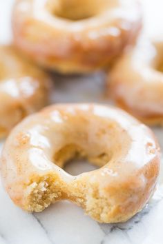 two glazed donuts sitting on top of a marble counter next to other doughnuts