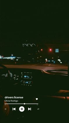 the dashboard of a car at night with lights in the background and an audio player on the dash board