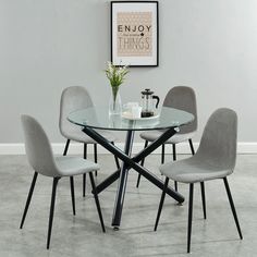 a glass dining table with four chairs around it and a vase on the table top