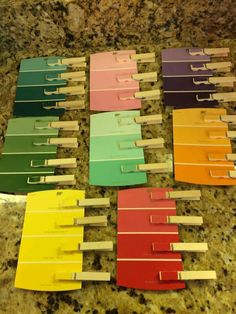 many different colors of clothes pegs on a counter with some paper clips sticking out of them