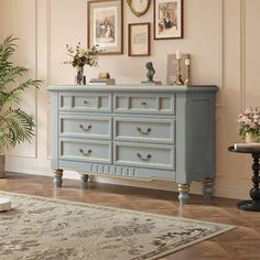 a blue dresser in a living room with pictures on the wall