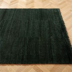 a large green rug on top of a wooden floor next to a hard wood floor