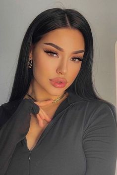 a woman with long black hair and gold jewelry on her neck is posing for the camera