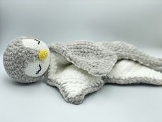 a crocheted stuffed animal laying on top of a white blanket with yellow eyes