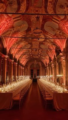 an ornate hall with tables and chairs covered in white tablecloths is lit by red lights