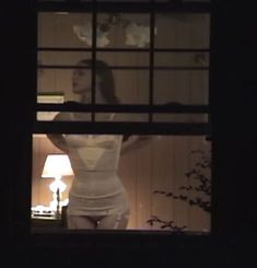 a woman standing in front of a window at night