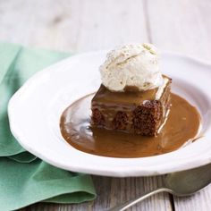 a piece of cake on a white plate with ice cream and caramel drizzle