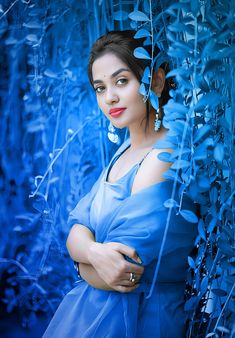 a woman in a blue dress is posing for the camera with her arms crossed and eyes closed