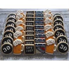 decorated cookies in the shape of beer mugs are arranged on a tray with black and white lettering