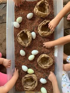 children are playing with an egg tray made out of sand and eggs on the ground