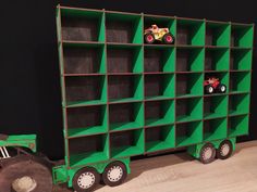 a toy truck and tractor are in front of a green bookcase that is on the floor