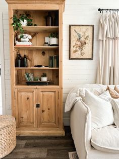 a living room with a white couch and wooden bookcase next to a large window