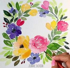 someone is painting a wreath with watercolors on paper