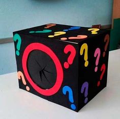 a black box with colorful question marks on the side and a clock in the background